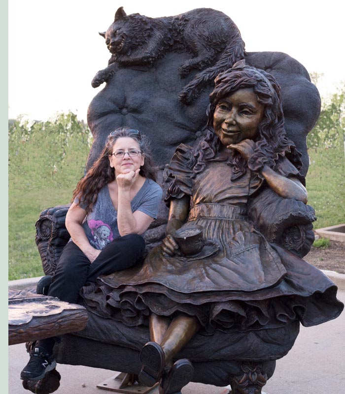 Bridgette Mongeon Sits in the bronze chair with Alice in Wonderland In Texas