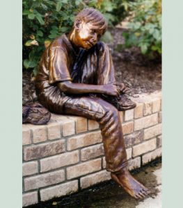 bronze statue of little boy tying his shoe tying