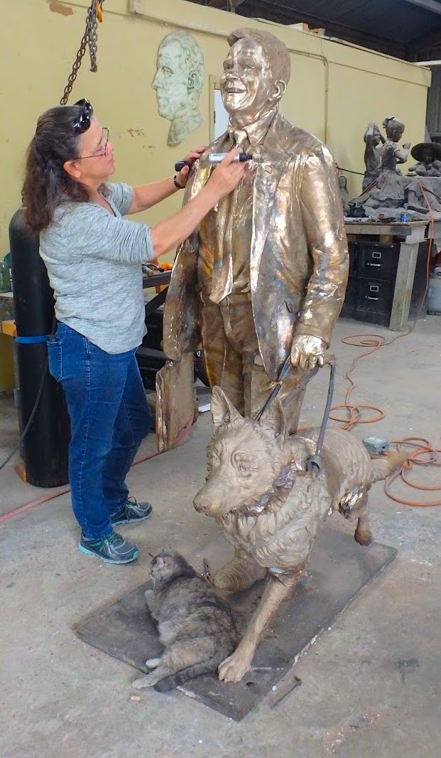 Sculptor Bridgette Mongeon looks over the metal of a bronze statue