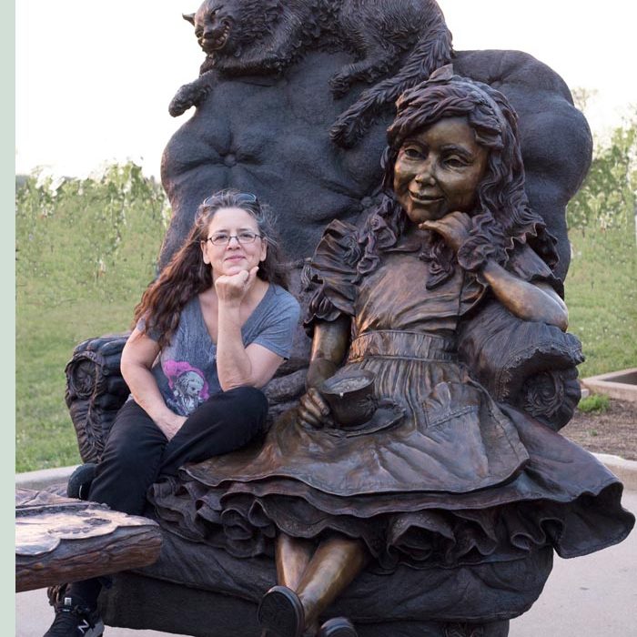 Bridgette Mongeon Sits in the bronze chair with Alice in Wonderland In Texas